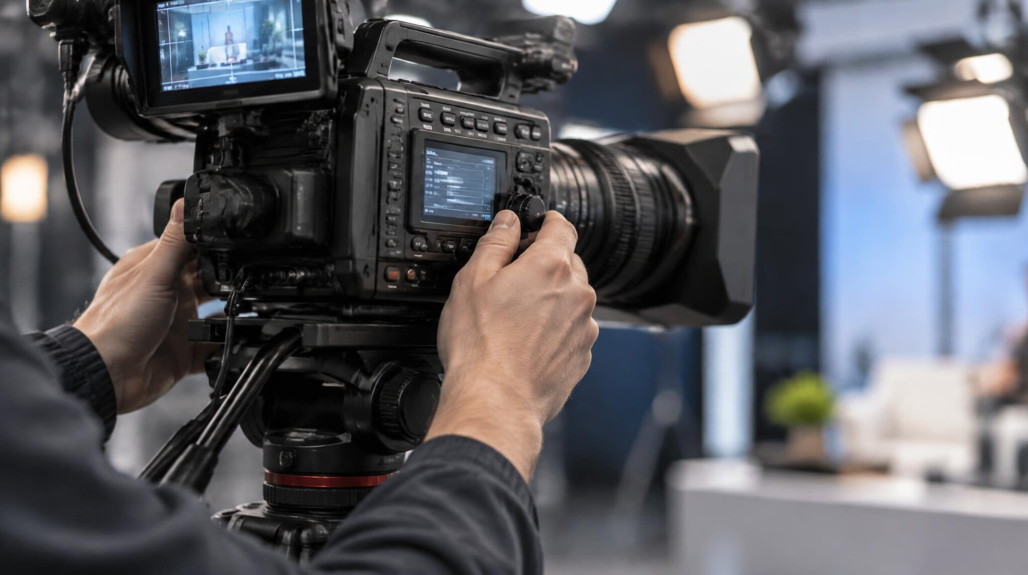 Camera operator adjusting a broadcast camera on a tripod